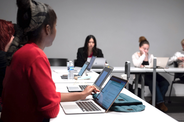 Students sitting in a classroom on their laptops.